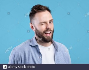 confident-handsome-caucasian-man-winking-and-smiling-at-camera-on-blue-studio-background-2DM1N0G.jpg